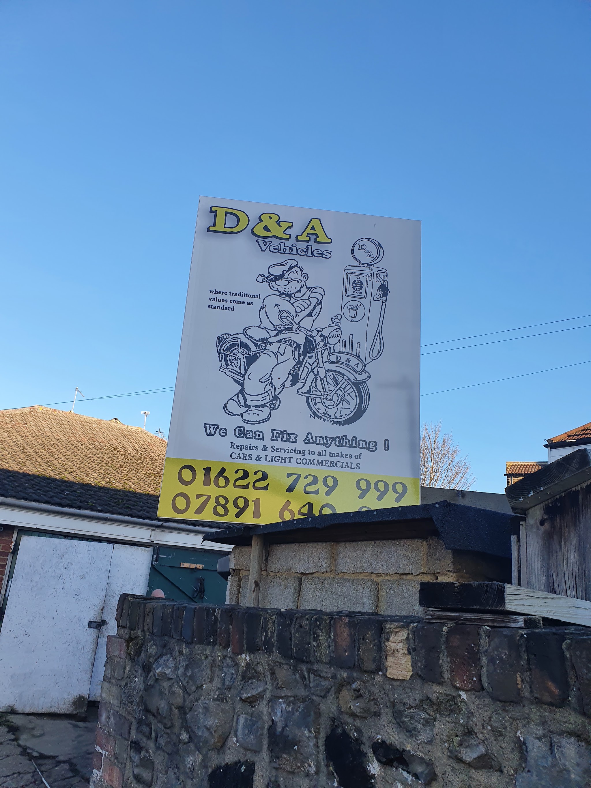 The D&A Vehicles sign above the workshop wall against a blue sky, with the phone numbers along the bottom